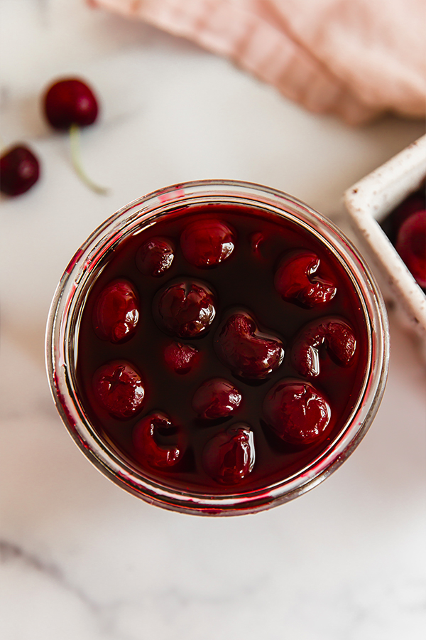 Top view of homemade maraschino cherries in glass jar
