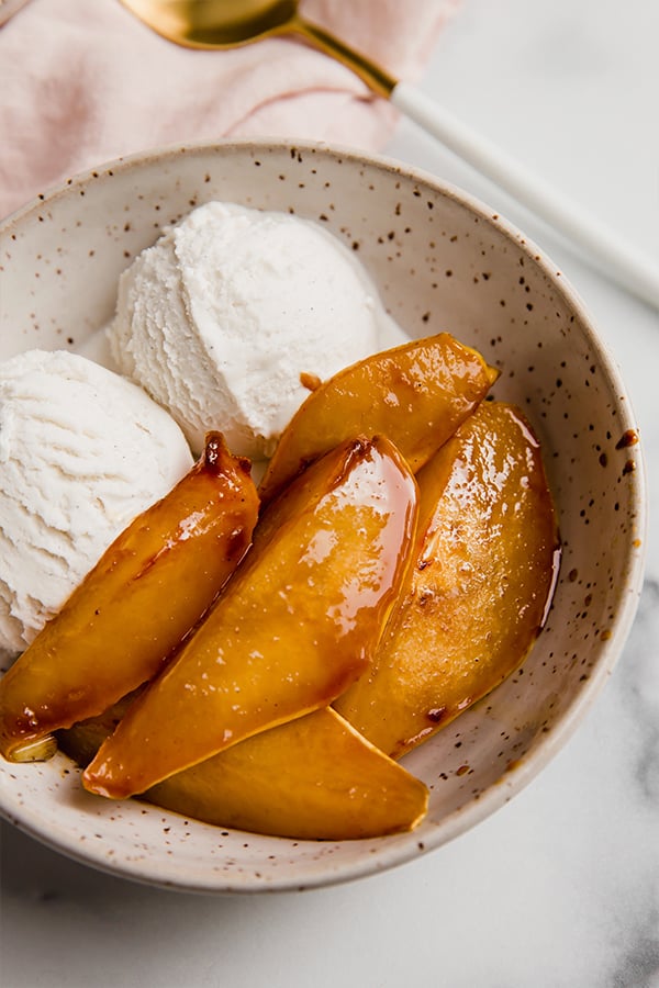 A bowl of caramelized pears with ice cream.