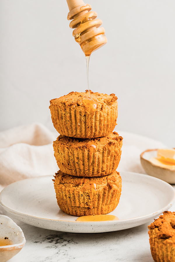 A stack of cornbread muffins with honey on top.