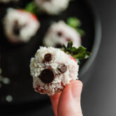 Person holding a strawberry decorated to look like a ghost.
