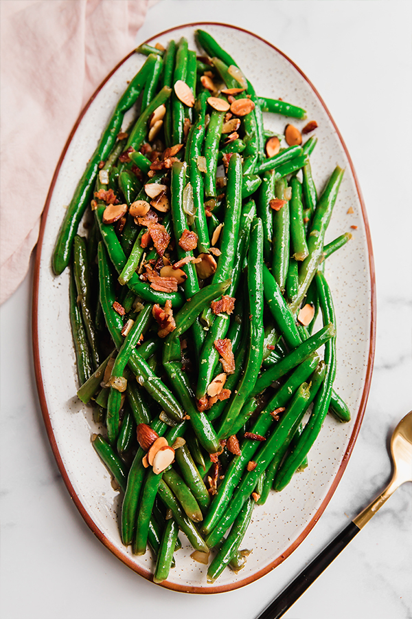 A platter of green beans with bacon and toasted almonds.