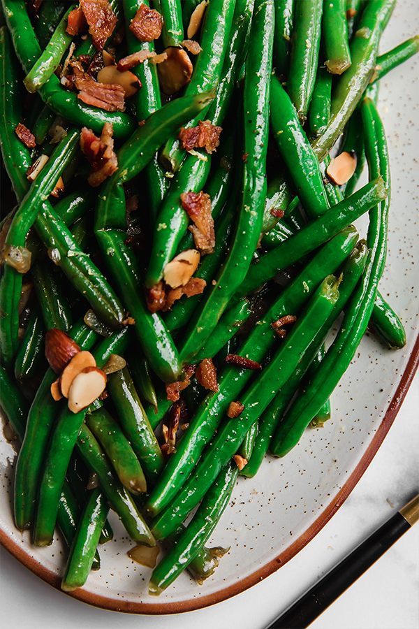 A close-up of green beans with bacon and toasted almonds.