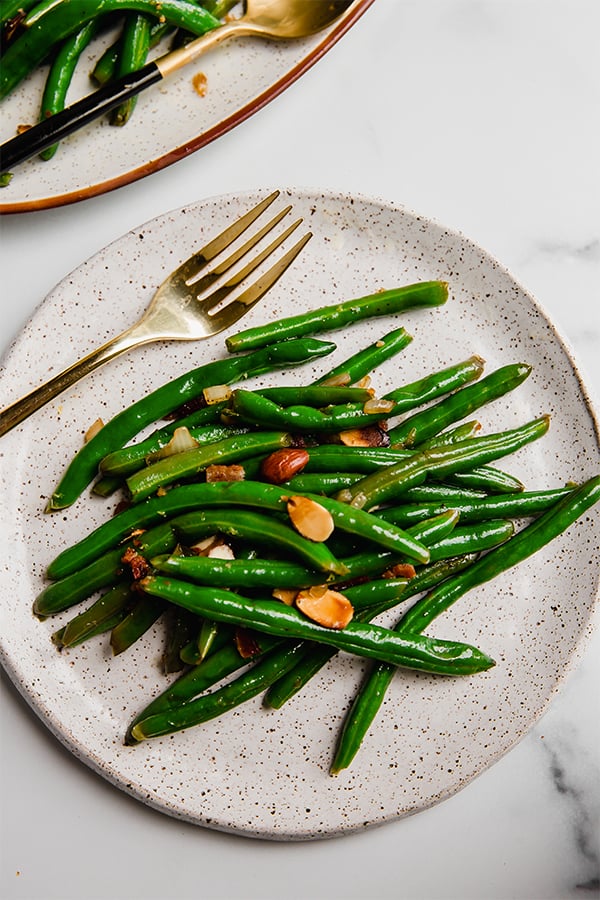 A plate filled with green beans with bacon and toasted almonds.