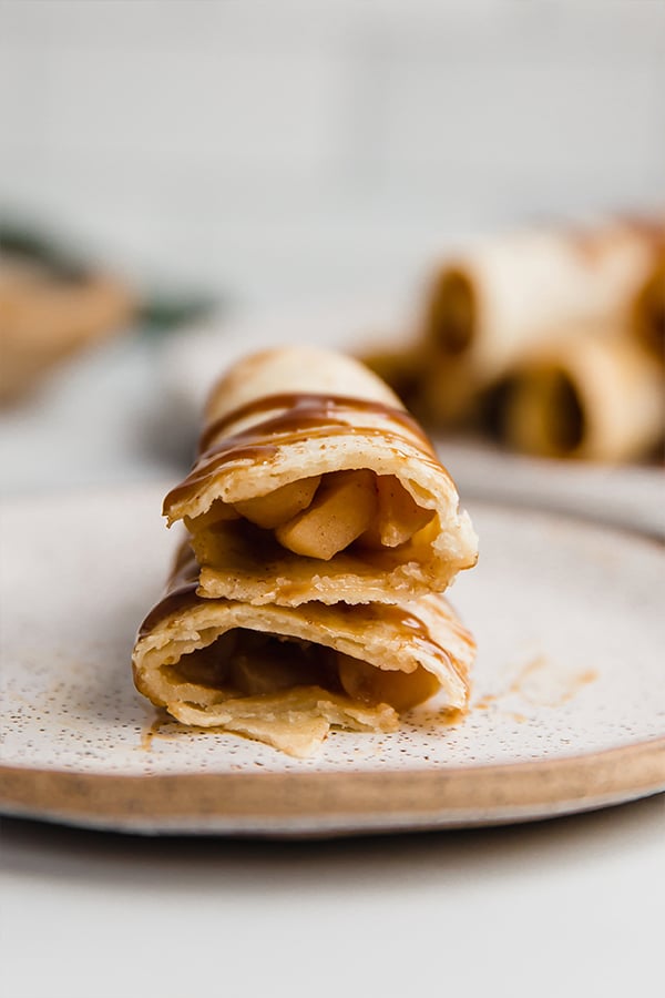 Two stacked apple pie roll-ups on a plate.