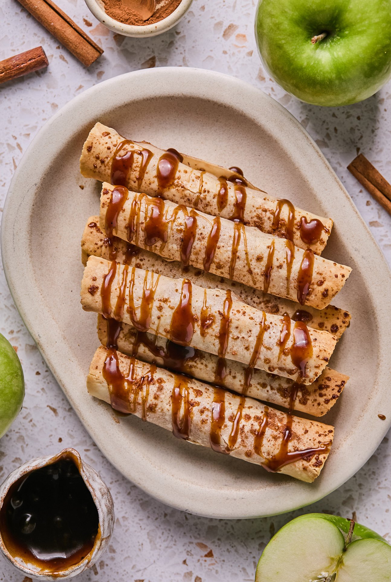 Apple pie roll ups on a platter drizzled with caramel. 