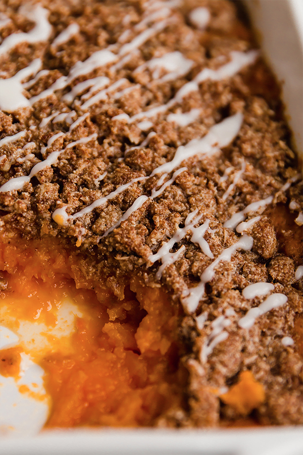 A pan of sweet potato casserole with a serving taken out.