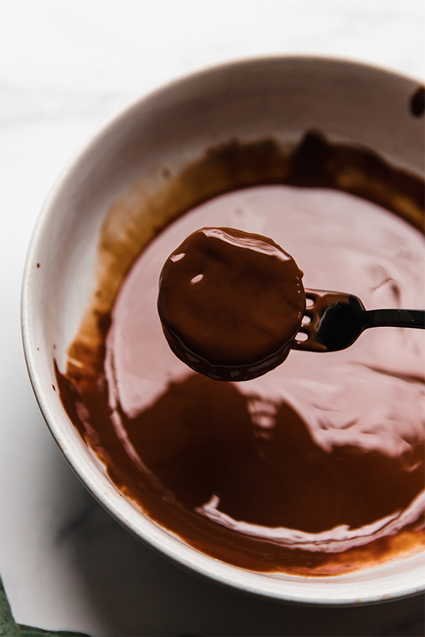 The cookie dipping into melted chocolate. 