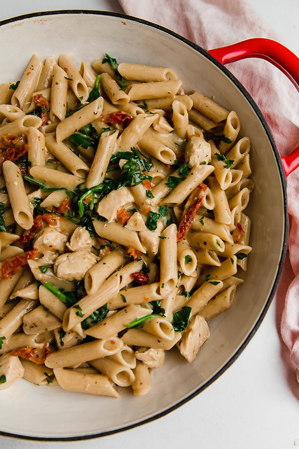 A dutch oven filled with creamy Tuscan chicken pasta.