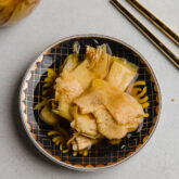 Chopsticks next to pickled ginger in a small bowl.