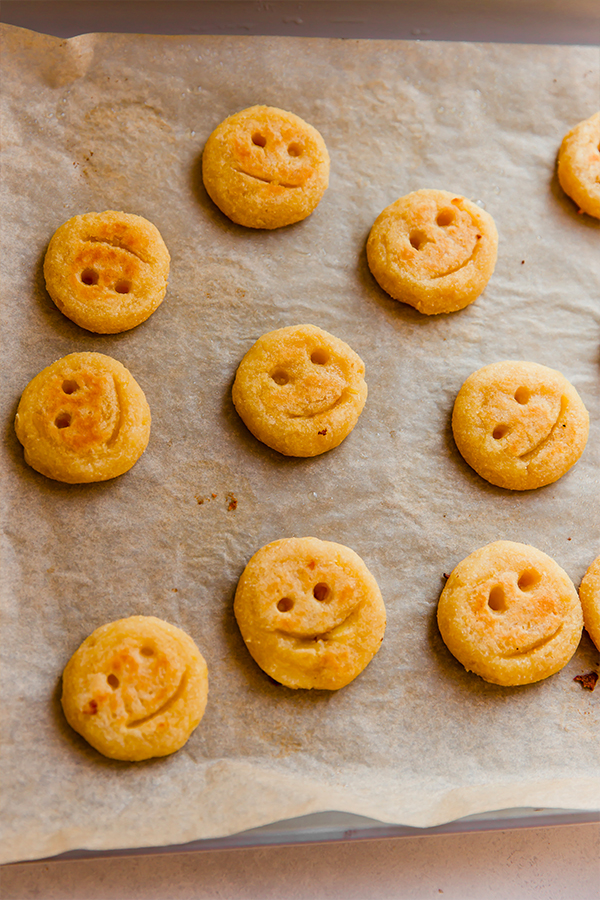 A baking sheet filled with baked sweet potato smiley fries.