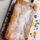 Loaf of applesauce pound cake on a colorful dish.