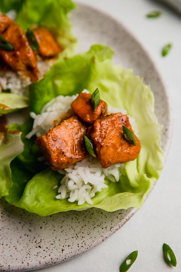 A plate with firecracker salmon lettuce cups on it.