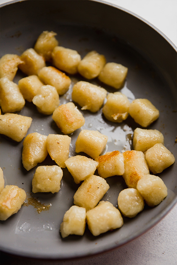 Gnocchi cooking in a skillet.