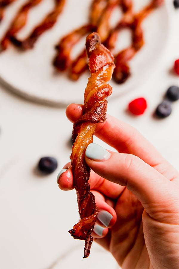 A hand holding one oven bacon twist.