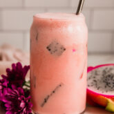 Dragon fruit drink in a glass with a straw.
