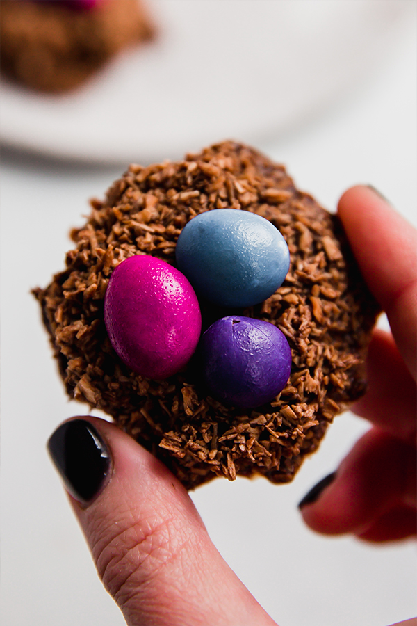One chocolate coconut Easter egg nests held between fingers.