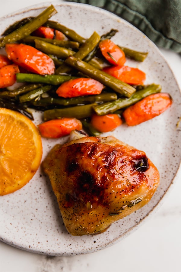A plate with citrus glazed chicken and vegetables on it.