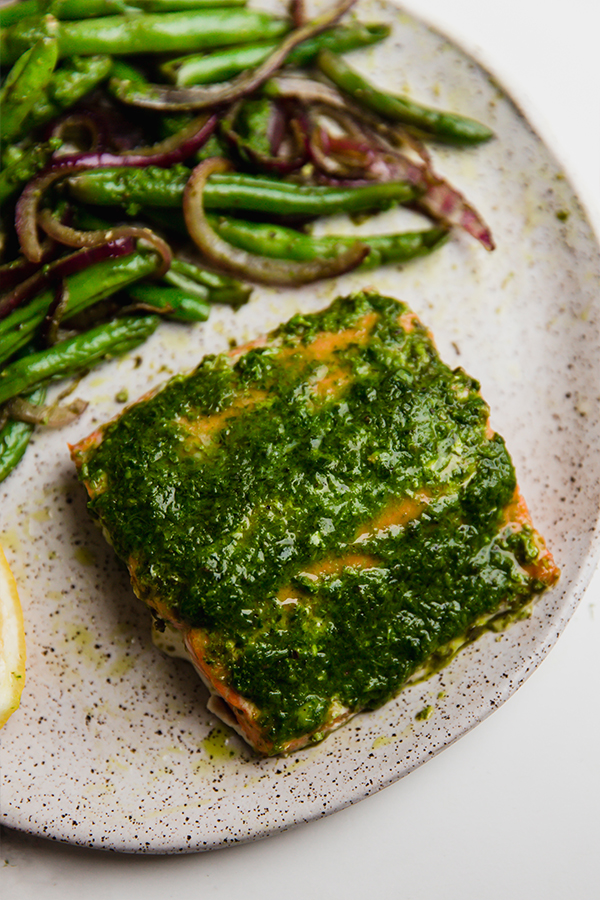 A plate with pesto salmon and vegetables.