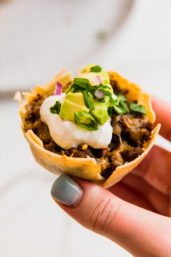 One mini taco cup being held by fingers.