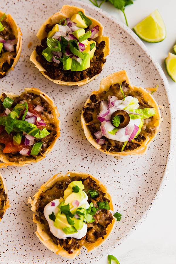 A plate with mini taco cups on it.