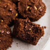 Chocolate zucchini muffins, one of which is missing a bite.