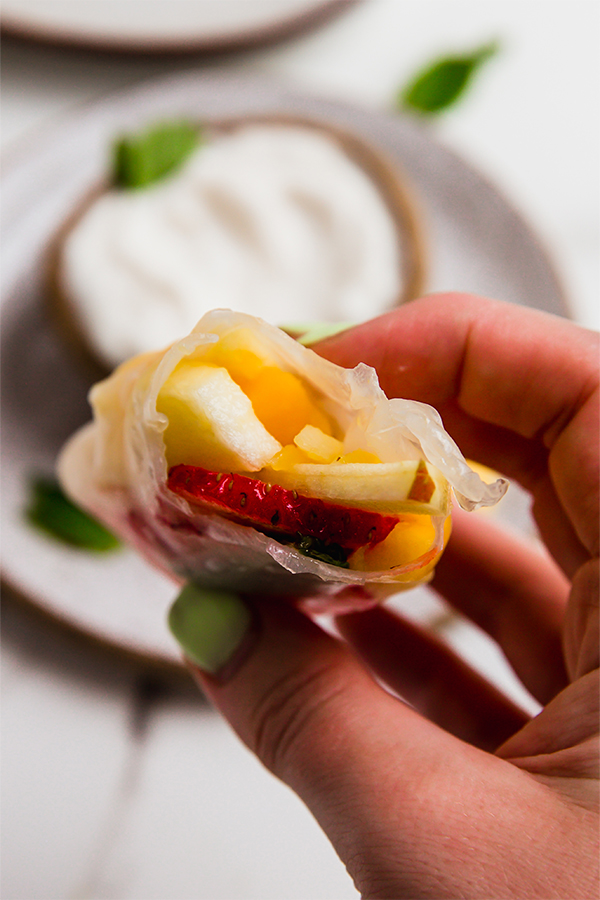 A fruit spring roll with a bite taken out of it.