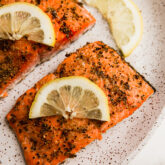Lemon pepper salmon on a plate with lemon slices.