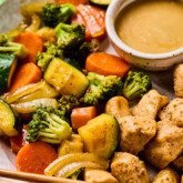 Hibachi chicken and vegetables with a side of mustard sauce on a plate with chopsticks.
