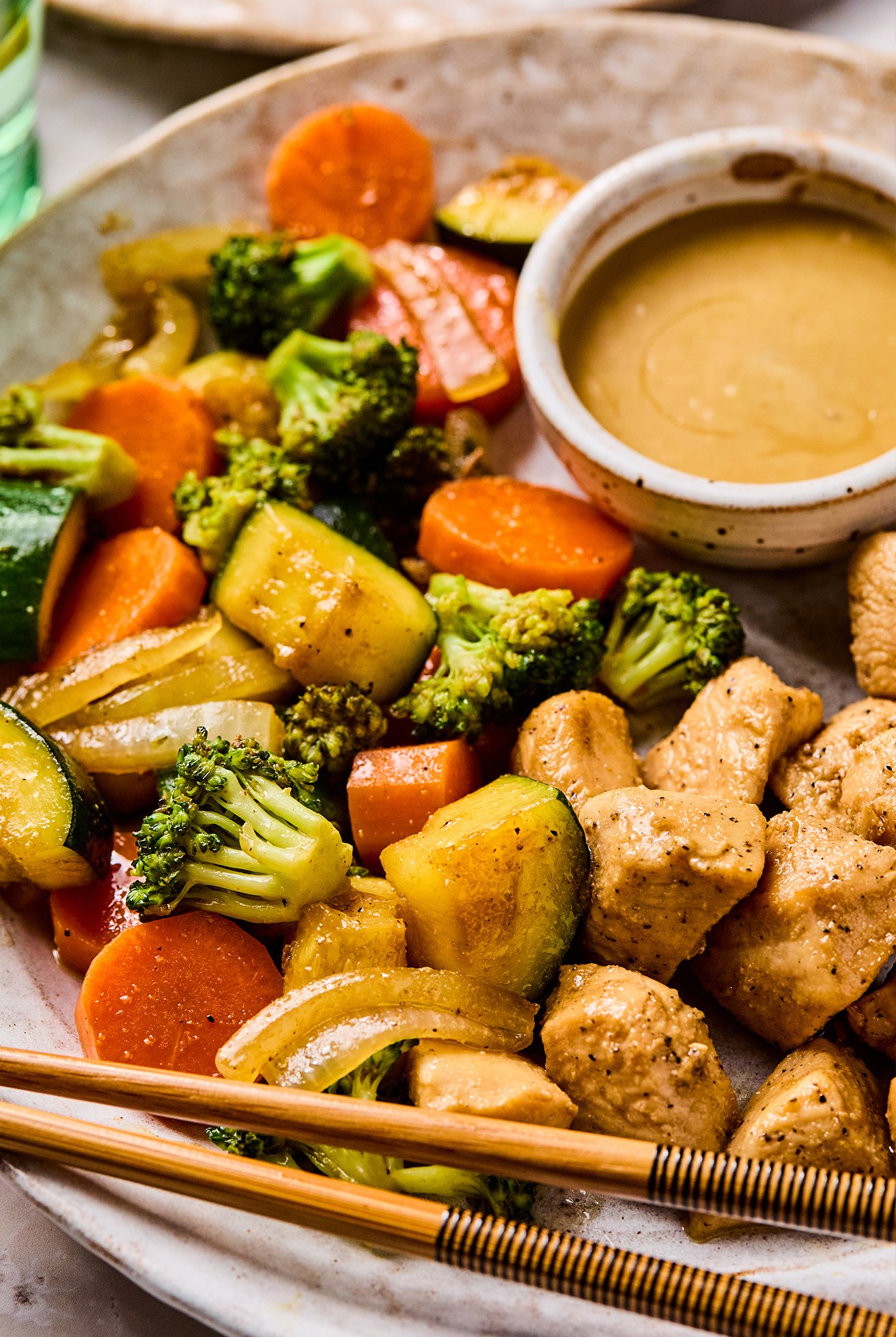 Hibachi chicken and vegetables with a side of mustard sauce on a plate with chopsticks.