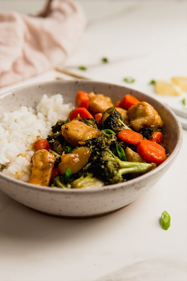 A bowl with rice and lemon chicken & vegetable stir fry.