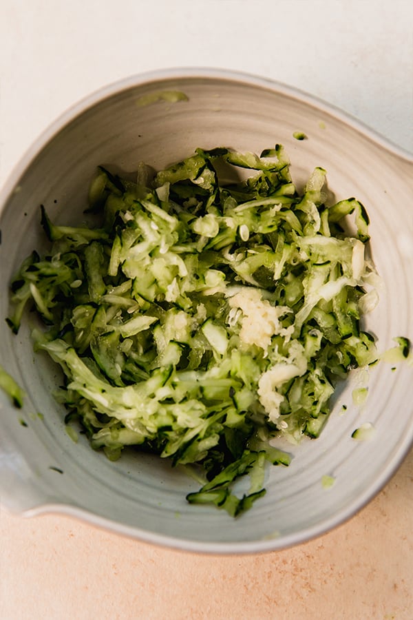 Grated zucchini and garlic in a bowl.