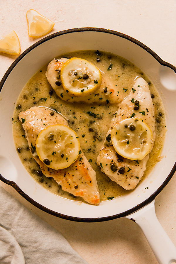 A pot of fully cooked chicken piccata.
