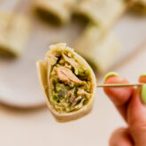 Person holding an avocado tuna salad pinwheel on a toothpick.