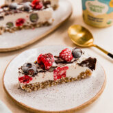 Slice of no bake berry vanilla ice cream cake topped with berries on a plate.