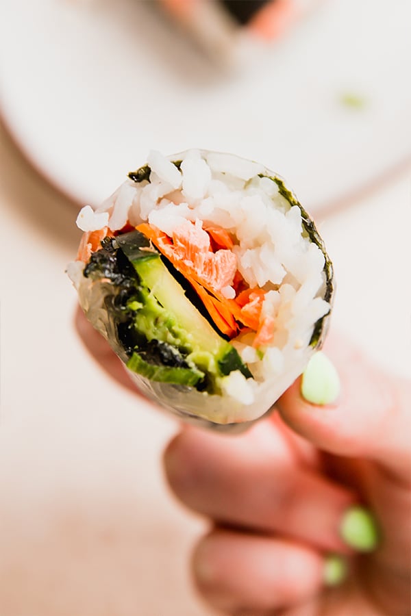 A sushi-inspired salmon rice paper roll with a bite taken out of it.
