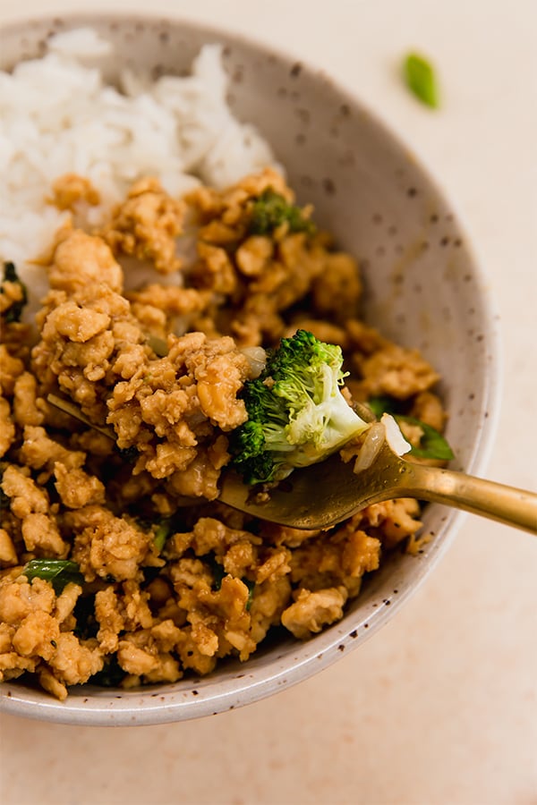 A bowl of ground chicken and broccoli with rice.