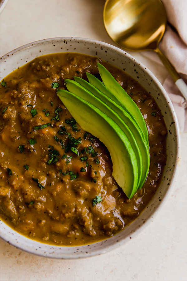 A bowl of dairy-free queso chili with avocado.