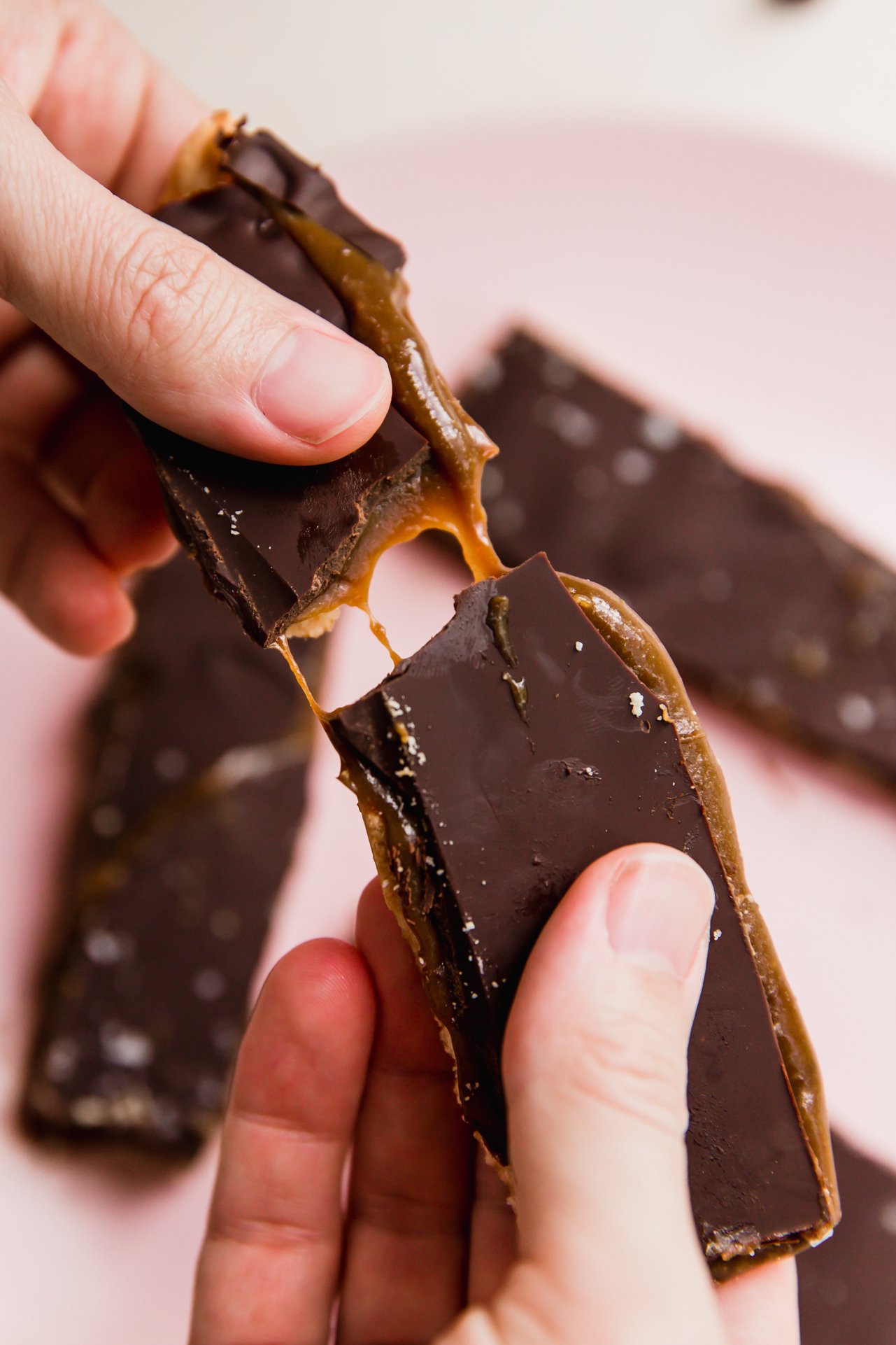 Homemade twix bar being broken in half with caramel pulling.