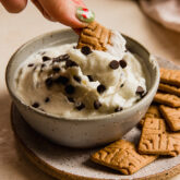 Person dipping a cookie into a bowl of cannoli dip.
