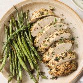 Turkey tenderloin sliced on a plate with green beans.