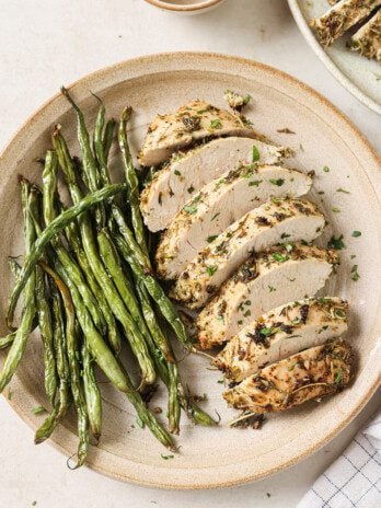 Turkey tenderloin sliced on a plate with green beans.