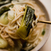 Spoon with a scoop of Bok Choy noodle soup.