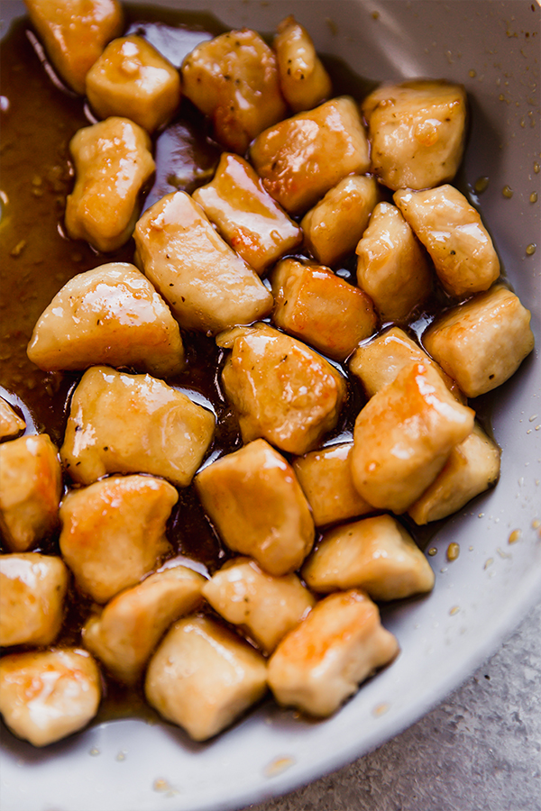 The honey butter chicken bites sauting in a pan