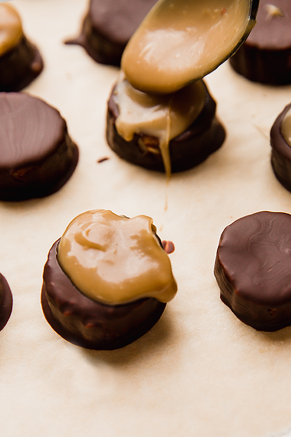 The chocolate covered banana bites with caramel being drizzled over them.