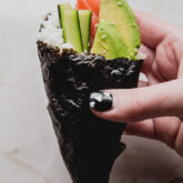 Sushi handroll with veggies coming out of the top.