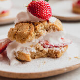 Plate with a strawberry shortcake missing a bite.