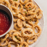 Crispy calamari on a plate with marinara sauce.