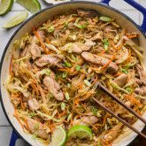 Pad woon sen in a large cast iron pan topped with limes.