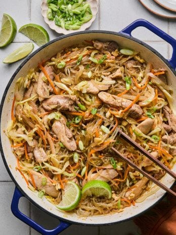 Pad woon sen in a large cast iron pan topped with limes.