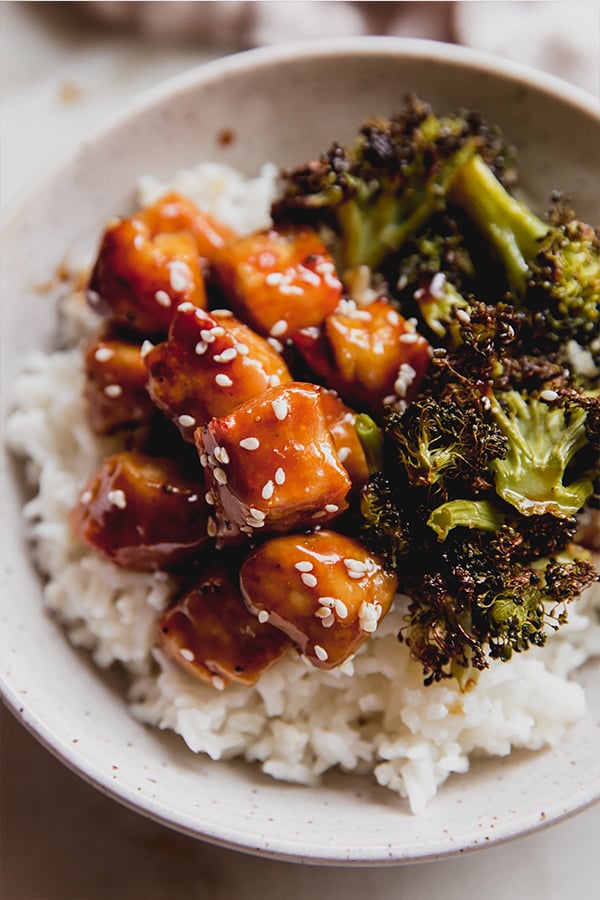 A bowl of sheet pan sesame chicken in a bowl ready to be eaten.